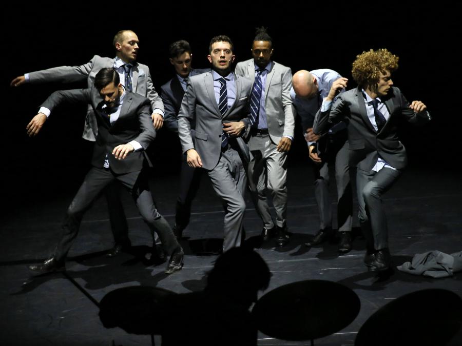 8 dansende mannen in pak. 